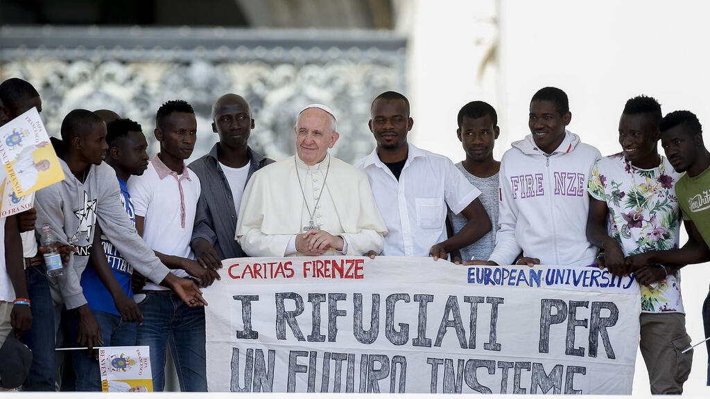 Un grupo de refugiados se toma una foto con el papa Francisco en los escalones de la Basílica de San Pedro, en 2016. Foto de ilustración.